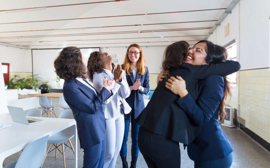 Mujer felicita a otra mujer, en una sala de juntas, para ejemplificar uno de los tipos de liderazgo femenino.