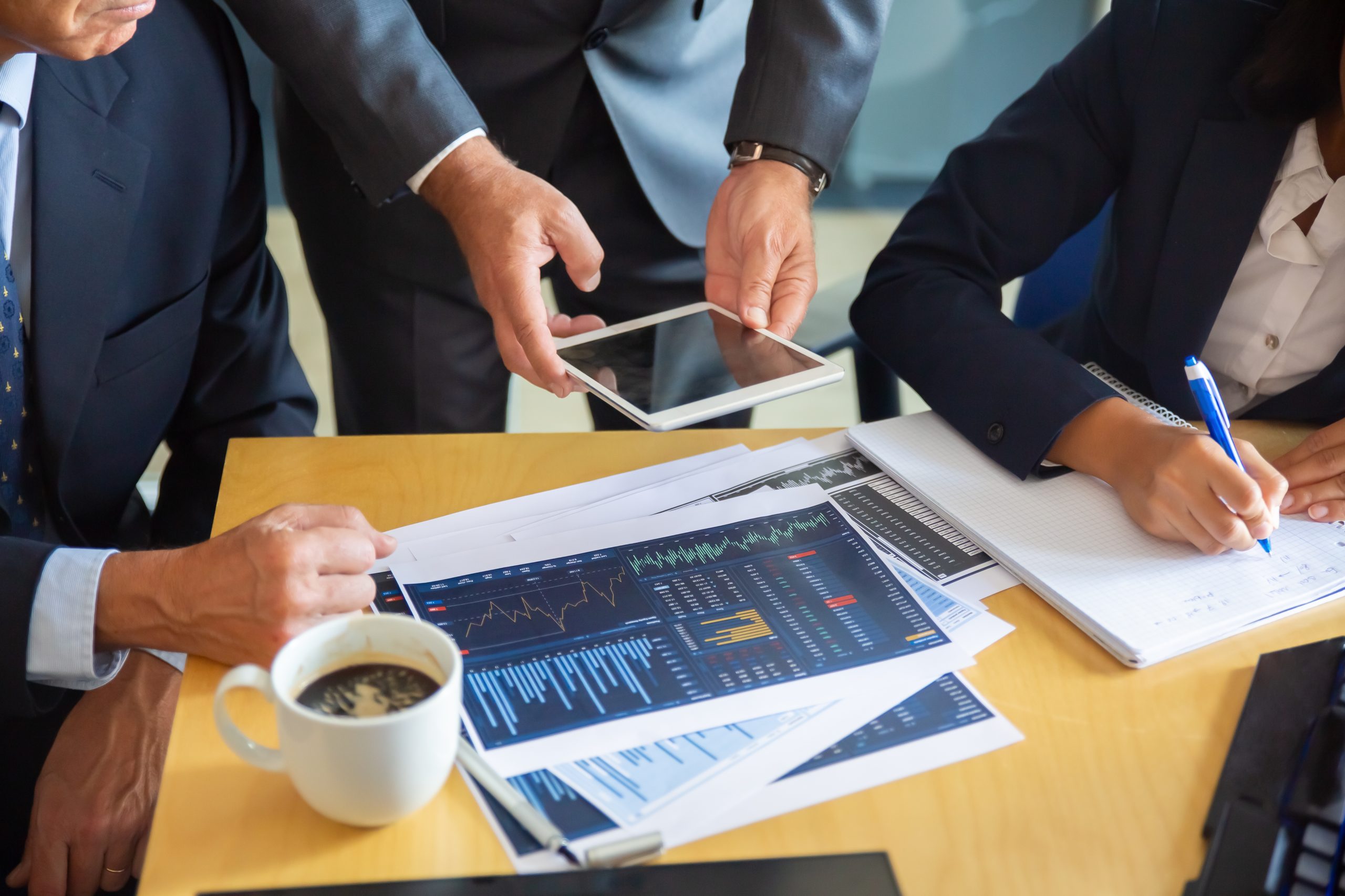 Profesionales revisando gráficos financieros, tablet y notas, analizando indicadores clave como EBITDA, ROA y rotación de inventarios. 