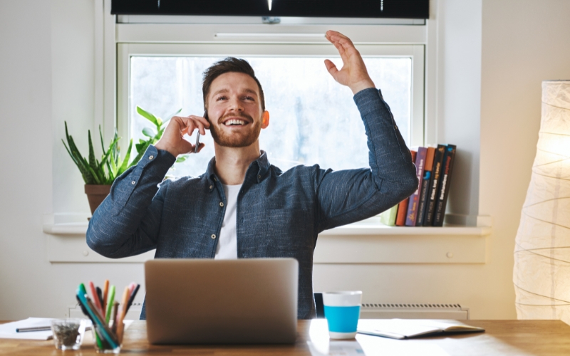 Emprendedor sonriente celebrando avances desde su oficina tras aplicar características clave de un emprendimiento de alto impacto