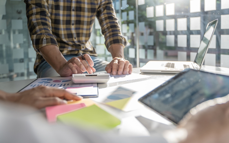 Personas evalúan gráficos y modelos de negocio en una mesa de trabajo para determinar si su idea encaja como una startup.