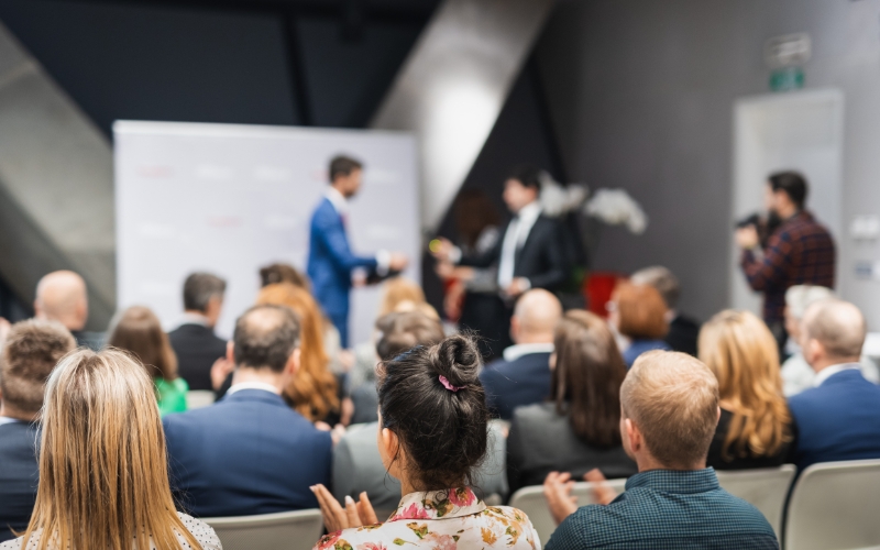 Audiencia atenta en evento donde se presentan ejemplos de emprendimiento de alto impacto con resultados sociales y globales