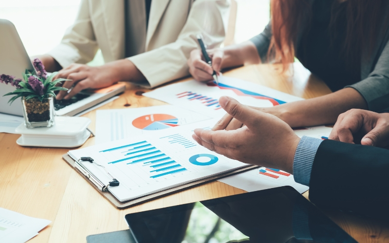 Personas analizan gráficas de crecimiento y validación en una mesa de trabajo, representando las fases de una startup.