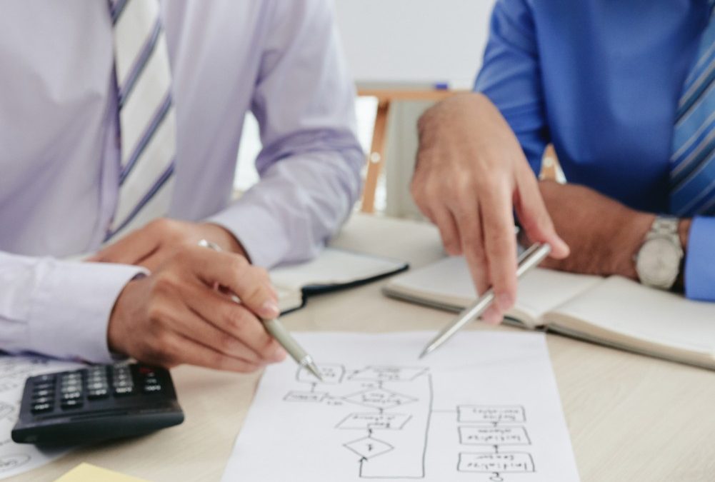 Vista de las manos de dos hombres que revisan un diagrama dibujado en un papel. La imagen ilustra las alternativas al plan de negocios tradicional.