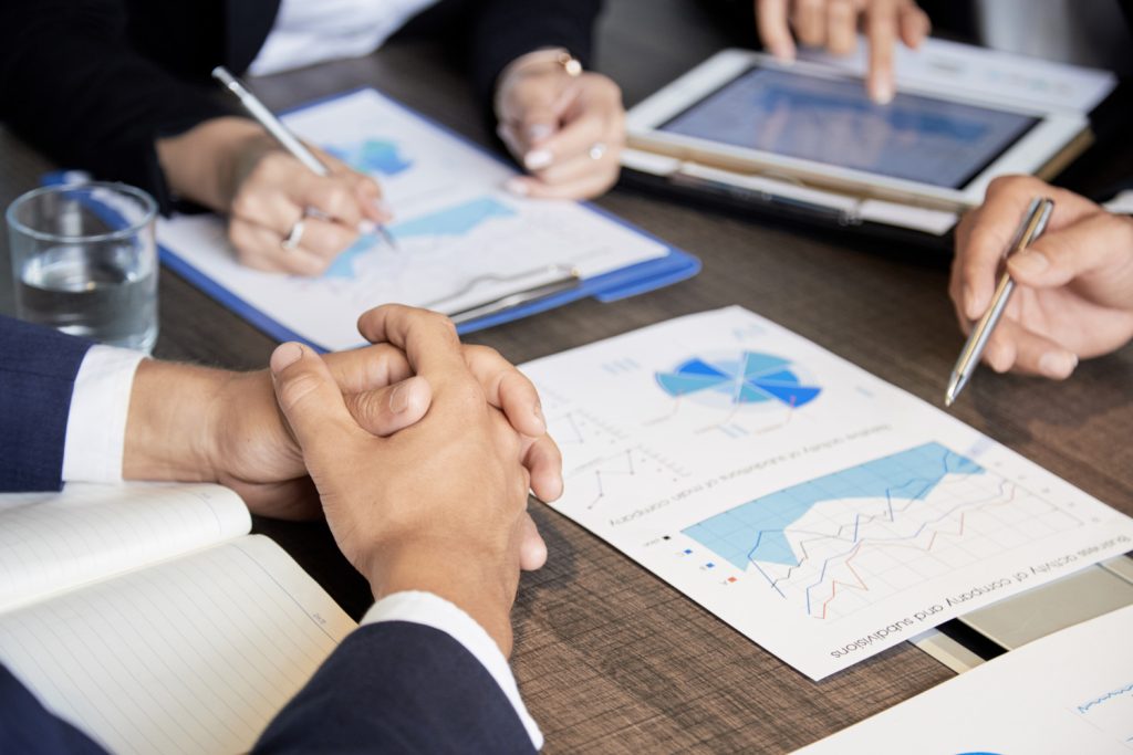 Vista de gráficas impresas y sobre una tableta electrónica, sobre un escritorio, para representar el análisis de costos.